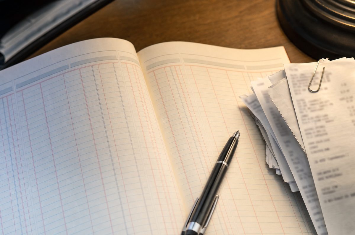 An open ruled ledger notebook with receipts clipped together on a desk